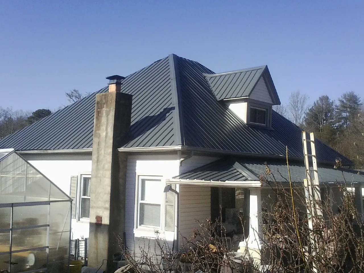 Dark blue standing seam metal roof on a white farmhouse with dormer — Slate & Tile Roof Repair by Roofing Brothers in Plainfield