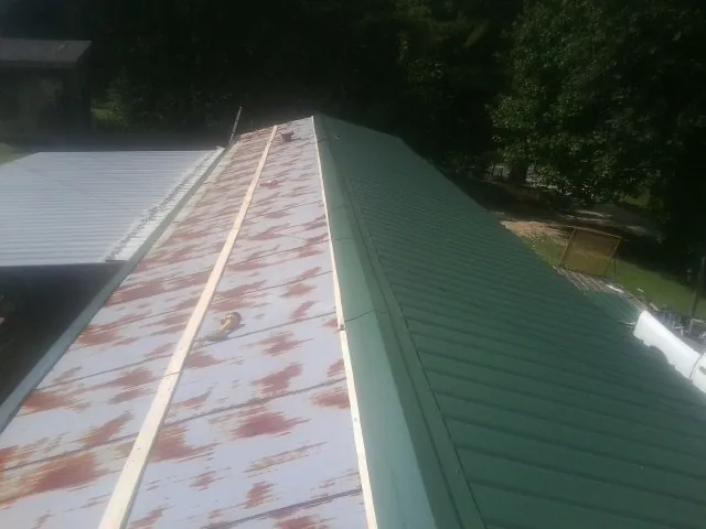 Old rusted panels beside newly installed green metal roofing — Wind Damage Roof Repair by Roofing Brothers in Plainfield