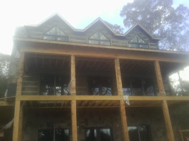 Dormers and porch framing on a large log home under construction — Roof Coating work by our crew in Plainfield